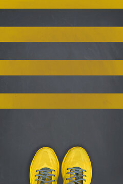 Yellow sneakers on grey background with pedestrian crossing lines on it. Trending colors of 2021. Minimal concept.