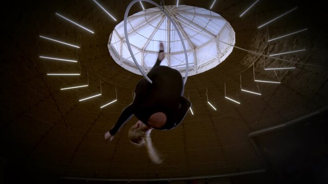 Gymnast female equilibrist upside down splits hang on aerial hoop. 