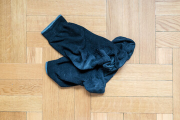 Dirty smelly black men socks lie in pile on wooden floor