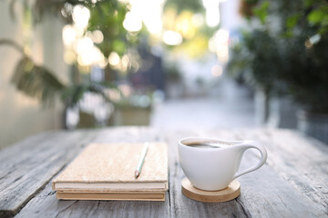 Coffee cup and brown kraft notebook and pencil on wooden table