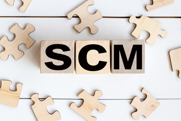 Supply Chain Management SCM. text on wood cubes on a light background. fold the puzzle