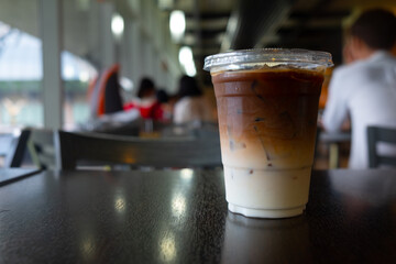 Iced latte coffee in plastic glass on wooden table.