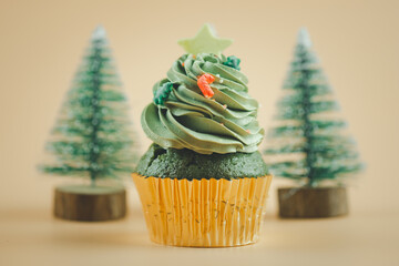 Christmas tree green cupcake in paper gold cup with Christmas tree background.