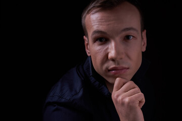 Close up portrait of a beautiful confident young man on a black isolated background in a Studio with copy space, he looks at the camera