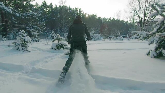 Cyclist in Black Clothes, Helmet and Snow Glasses Riding on Electric Bike in the Snow in Winter Forest. E-Bike Riding and Drifting at Cold Sunny Day - Super Slow Motion