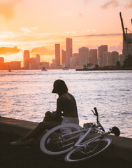 silhouette of a person on a bicycle woman cap sunset skyline buildings city miami florida looking...