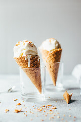 close up of two white ice creams in waffle cups on gray background