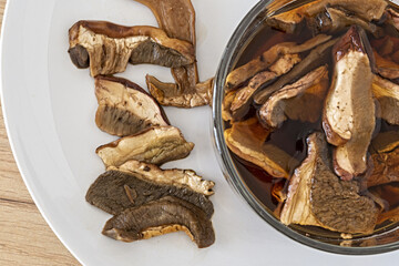 piatto e tazza di vetro con funghi porcini secchi in ammollo vista dall'alto macro