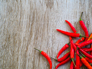 Red peppers stacked together on a wooden floor, taken from the top corner.