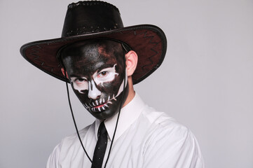 a man in halloween makeup as a dead man with a black skull in a cowboy hat and tie