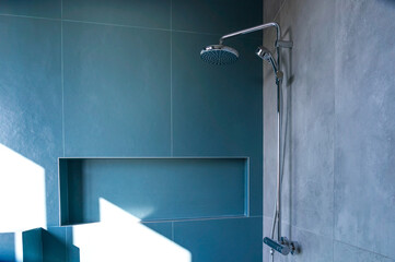 Shower cubicle cladding in blue porcelain stoneware illuminated by the bright sun