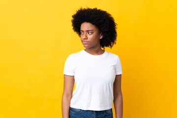 Young African American woman isolated on yellow background having doubts while looking side