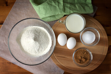 The necessary set of ingredients for making pancakes and pancakes eggs flour salt sugar and milk.
