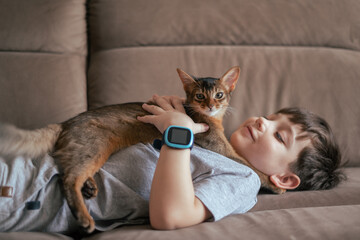 Little kid boy with his cat pet on the couch. Children and love pets concept