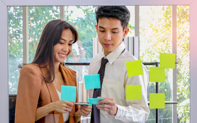 Asian businessmen and women looking and writing post-it notes for brainstorming