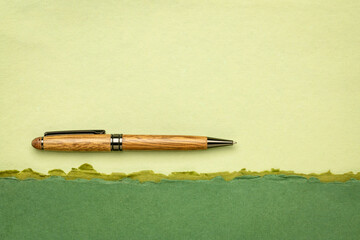 abstract paper landscape in green pastel tones with a stylish pen and a copy space