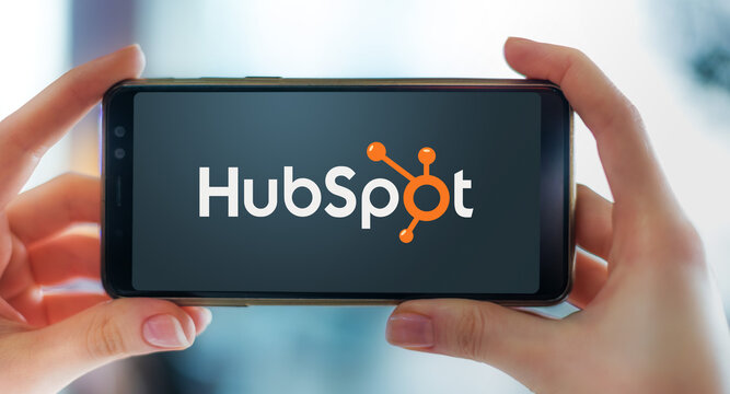 Hands Holding Smartphone Displaying Logo Of HubSpot