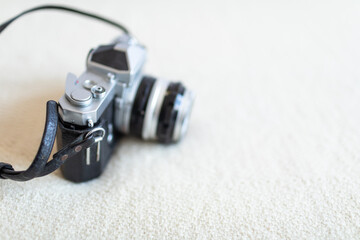 Antique film camera on white blanket on a bed by the window. Stylish hobby time.