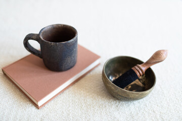 Singing bowl or Tibetan bowl on white blanket with a cup drink, tea or coffee. Mindfulness relaxation time.