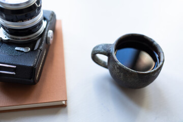 Cup of tea or coffee in a mug with a book and vintage camera.