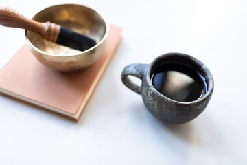 Singing Singing bowl or Tibetan bowl on white table with a cup drink, tea or coffee. Mindfulness relaxation time.