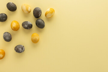 Golden and silver easter eggs scattered on yellow background, festive easter concept