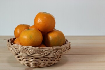 Orange fruits in a wooden tray on wooden background