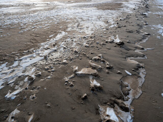 Frozen beach sand with ice and snow in an abstract view