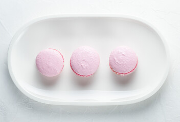 French macaroni cakes on a white oval plate on a light background