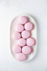 French macaroni cakes on a white oval plate on a light background