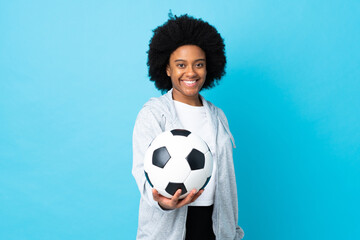 Young African American woman isolated on blue background with soccer ball