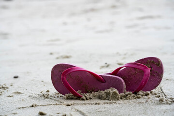 Summer holiday beach background with flip flops on a tropical beach. Red Slippers from a sand on a beach, relax concept