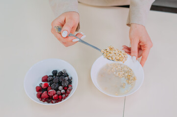 Mom prepares oatmeal with honey and fruit in the kitchen.