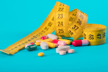 Diet concept. Slim by pills, dangerous for health. Centimeter tape and pills on a colored background with space for text. concept of losing weight, diet, fat burning, healthy eating. minimalism.