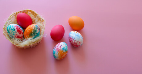 Happy Easter holiday! Colorful hand-painted Easter eggs in a decorative nest on pink background.