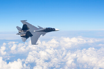 Fototapeta na wymiar Combat fighter jet flies turning maneuver high in the sky above the clouds.