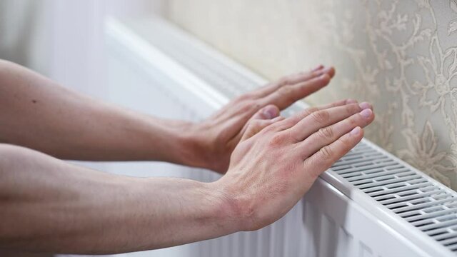 Man checks the temperature of the heating radiator