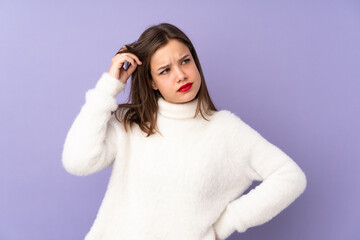 Naklejka premium Teenager girl isolated on purple background having doubts and with confuse face expression