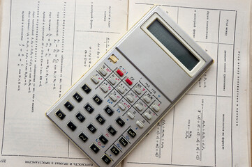 An old metal calculator on the math reference book with calculation formulas