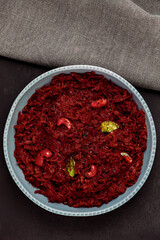 Beetroot curry made from grated beetroot with coconut milk, grated coconut and cashews. Indian cuisine meal in plate placed on black slate. Top view.