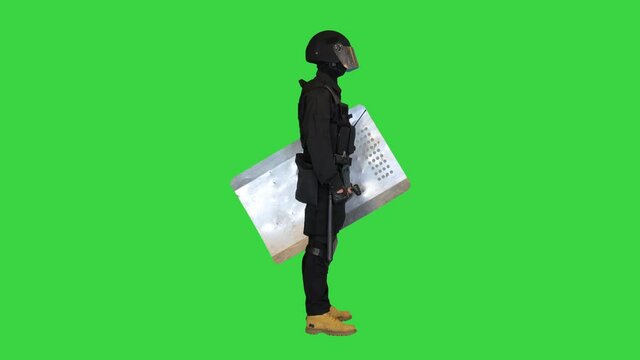 Policeman in full riot gear standing with the shield down on a Green Screen, Chroma Key.