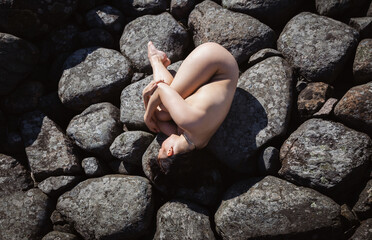 Nude woman posing on a stone pier