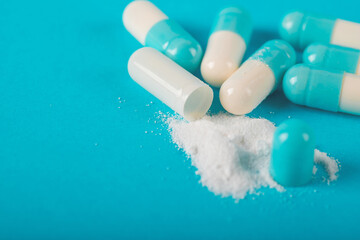 Blue and white capsule pills on blue background. Antibiotics drug resistance. Antimicrobial capsule pills. Pharmaceutical industry. Healthcare and drugstore. Pharmaceutics concept. Drug in hospital. 