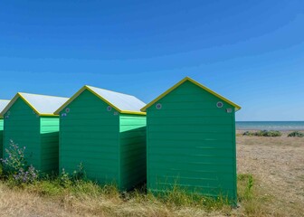 Fototapeta na wymiar bright green beach huts on the seashore