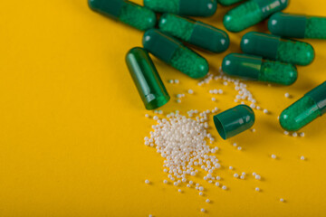 green capsule pills on yellow background. Antibiotics drug resistance. Antimicrobial capsule pills. Pharmaceutical industry. Healthcare and drugstore. Pharmaceutics concept. Drug in hospital. 