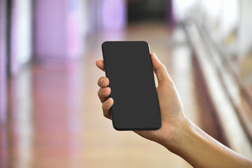Blank screen mobile phone holding in hands of female student, soncept for using mobile phone to contact with parents at home when student was at school. Soft and selective focus on mobile phone.