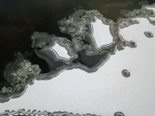 Aerial drone top view. Frosty pattern drawing on the river. Cloudy frosty winter morning.