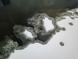 Aerial drone top view. Frosty pattern drawing on the river. Cloudy frosty winter morning.