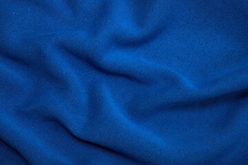 Fototapeta na wymiar Pleats on fabric, knitted material of bright blue color, folds