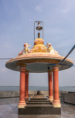 Bagalkot, Karnataka, India - November 8, 2013: Sri Sangameshwar Temple. Shivalingam under colorful baldachin with Nandi bulls over Krishna River under blue sky. © Klodien